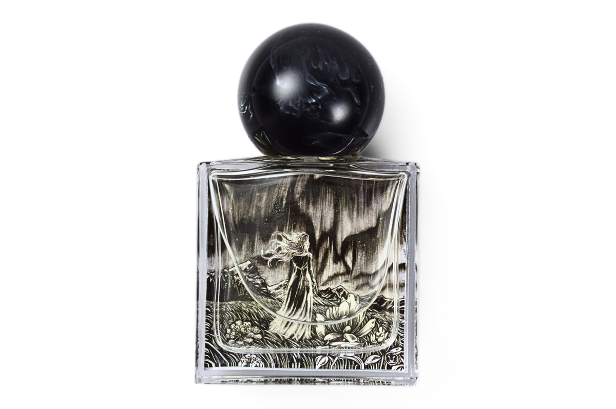 Aurora Borealis parfum in a clear square glass bottle with black marble-patterned round resin cap and etched floral artwork