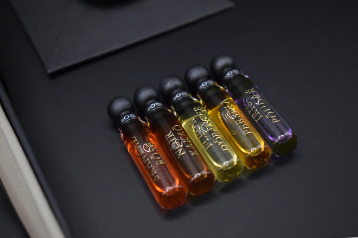 Discovery Set of five slim glass perfume sample vials in amber, orange, yellow, and purple with black caps