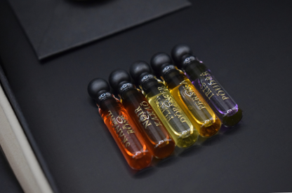 Discovery Set of five slim glass perfume sample vials in amber, orange, yellow, and purple with black caps