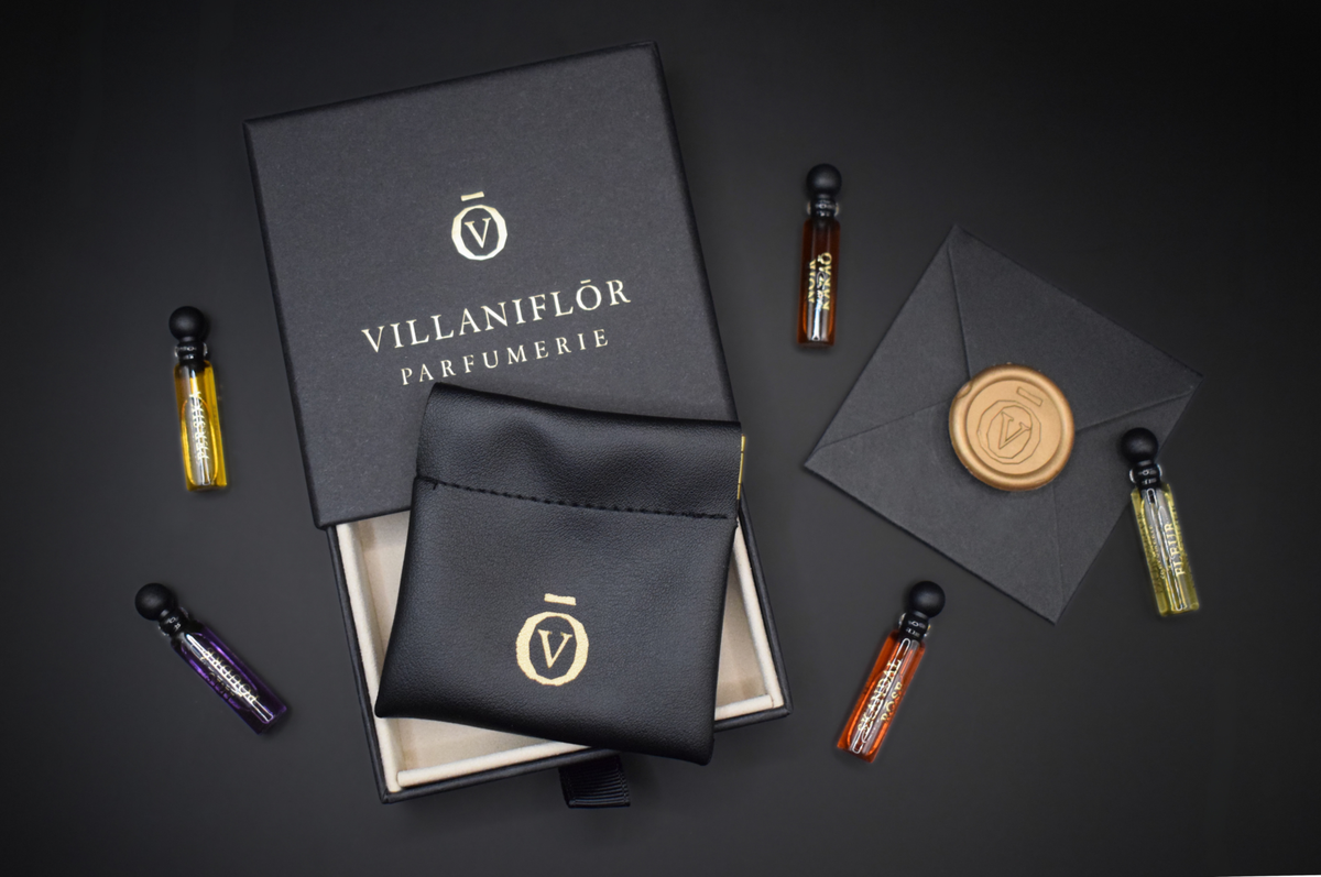Discovery Set perfume samples in five slim glass vials with a charcoal box, black fabric pouch and gold branding
