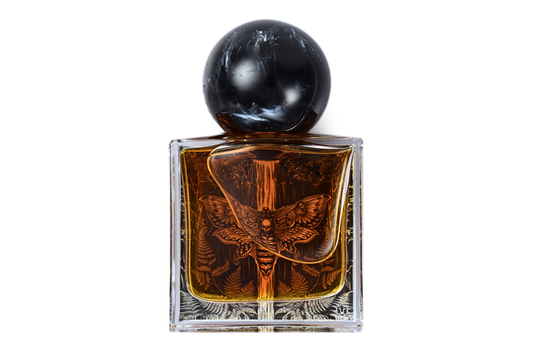 Fern Valley parfum bottle with amber liquid, clear glass, black marble cap, and moth with fern pattern