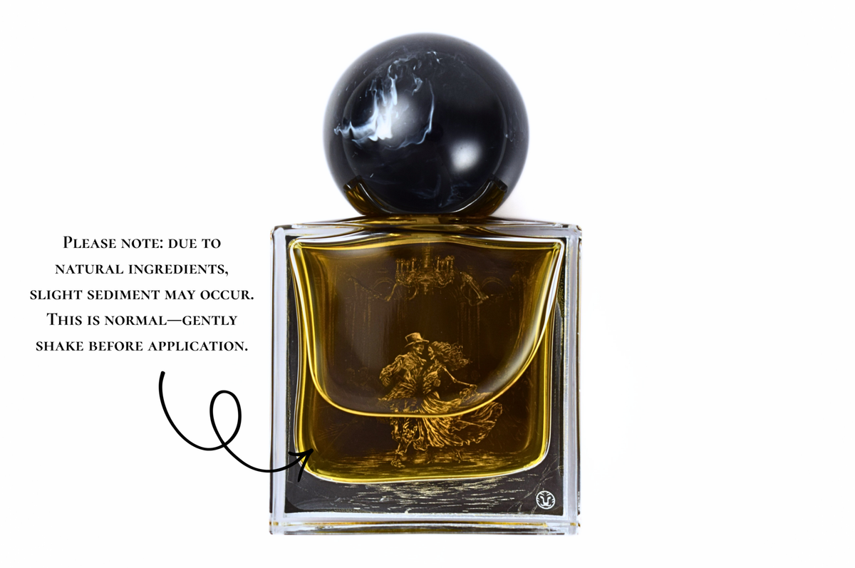 MACABRE parfum bottle with amber liquid, clear glass, black spherical cap, and ornate gold figure detail