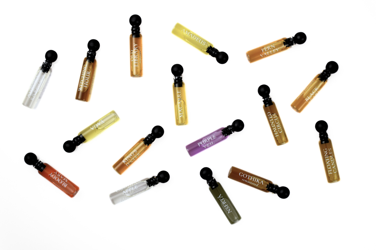Quadro Set of assorted perfume sample vials in amber, yellow, purple, green, red, and clear glass with black caps