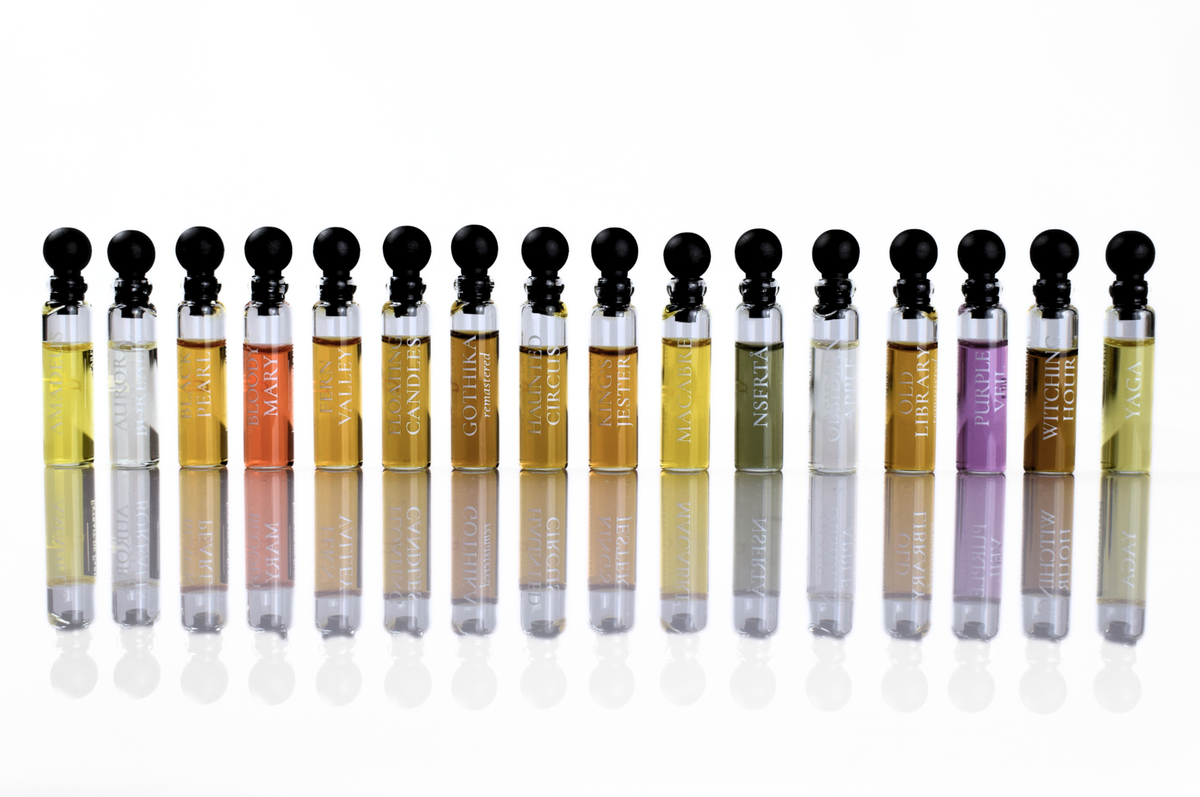 Quadro Set of unisex parfum sample vials with black caps, clear glass bottles, and assorted coloured fragrances