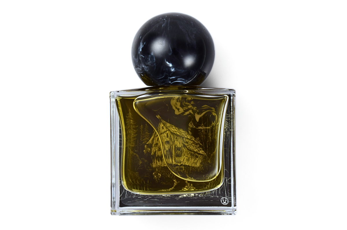YAGA parfum bottle in clear glass with amber liquid, black marbled round cap, and etched forest illustration