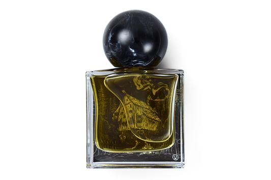YAGA parfum bottle in clear glass with amber liquid, black marbled round cap, and etched forest illustration