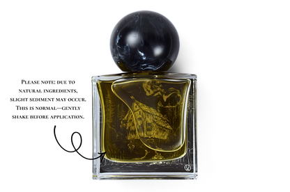 YAGA parfum in a clear square glass bottle with dark amber liquid, black marbled round cap, and forest illustration